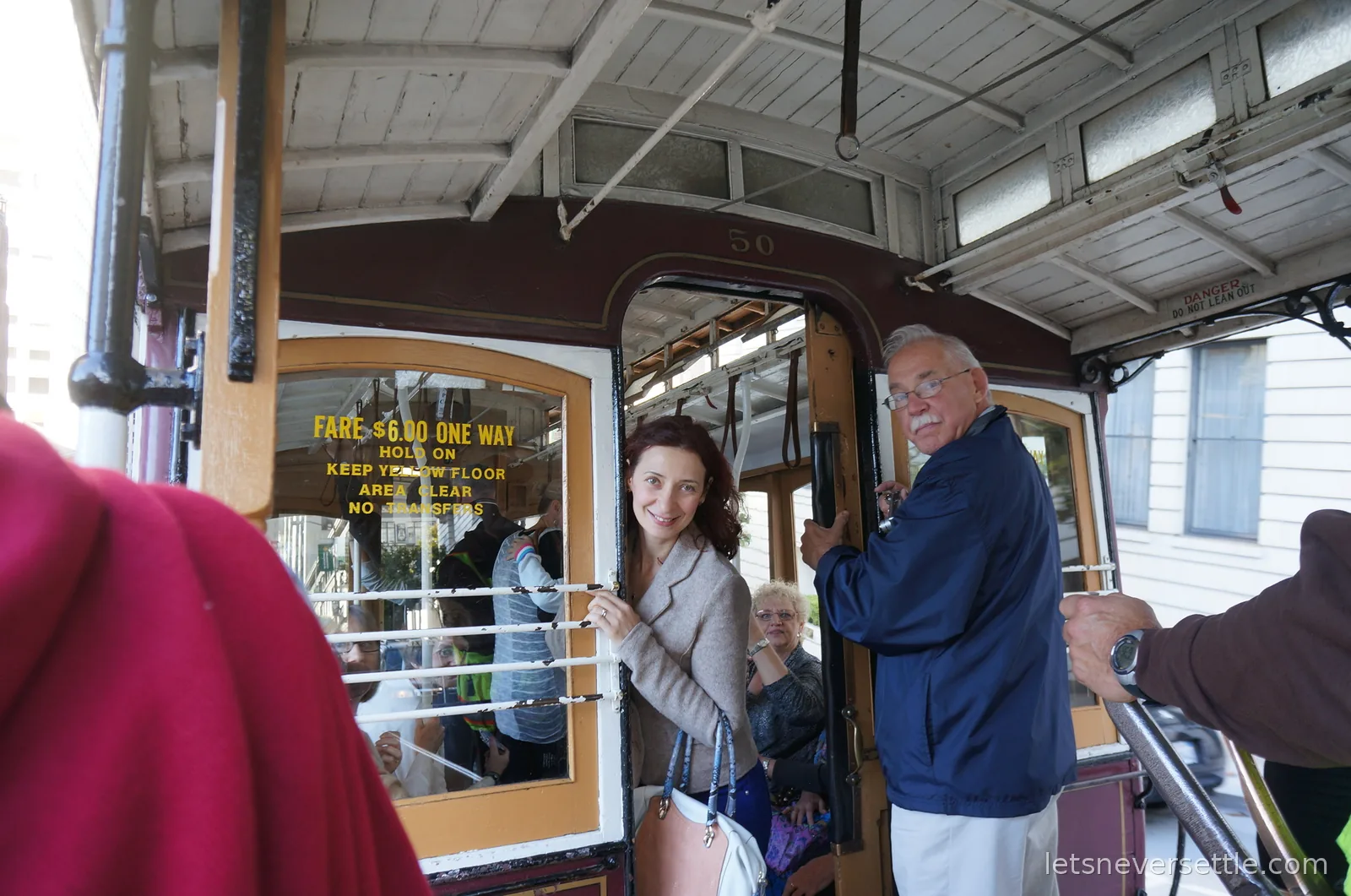 Inga smiling aboard a cable car beside the yellow fare sign reading six dollars one way