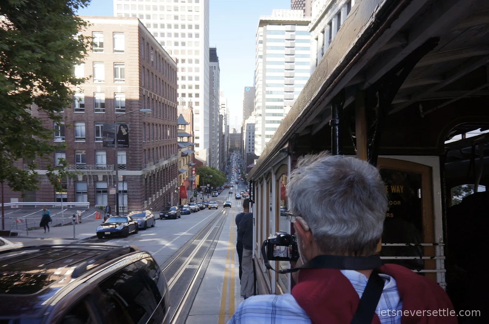 Looking down California Street from a moving cable car as the tracks drop between office towers towards the bay