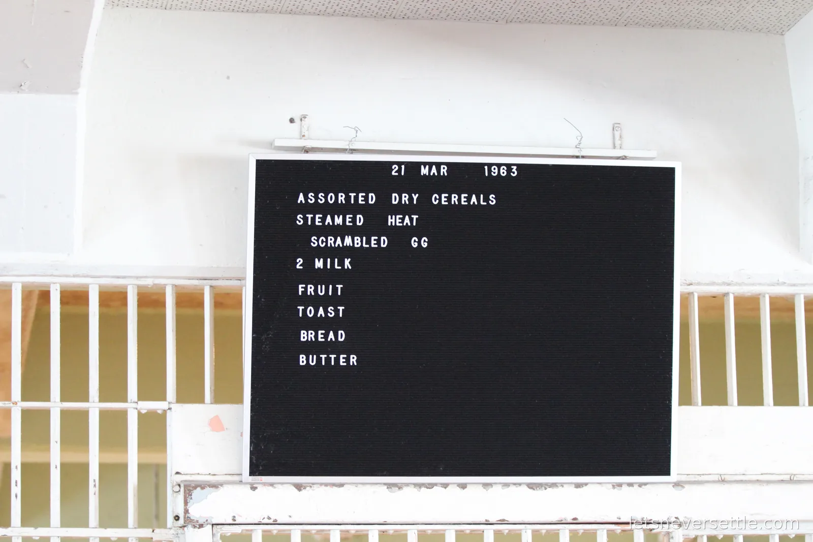 Black menu board in the Alcatraz dining hall dated 21 March 1963, listing dry cereals, steamed wheat, scrambled eggs, milk, fruit, toast, bread and butter