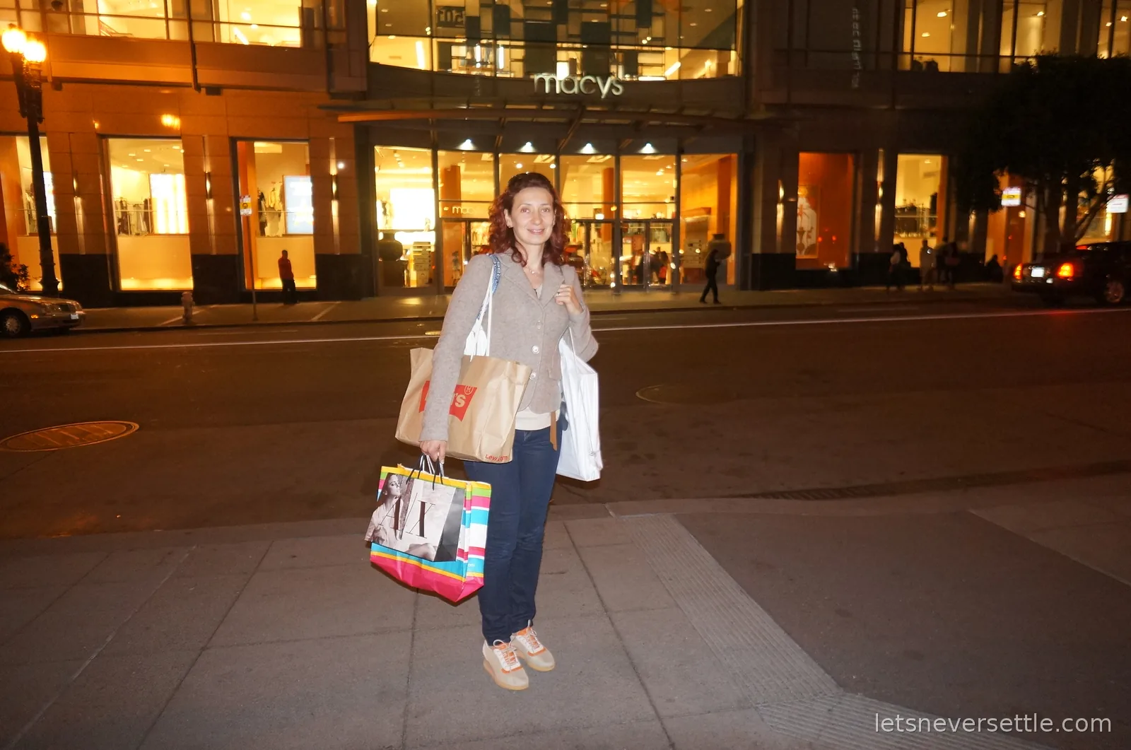 Inga holding several shopping bags outside the lit Macy's storefront at night