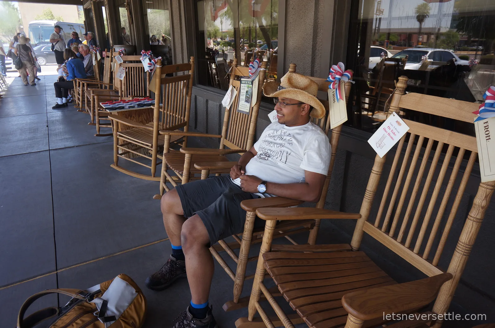 Dileep sitting in a wooden rocking chair on the Cracker Barrel front porch