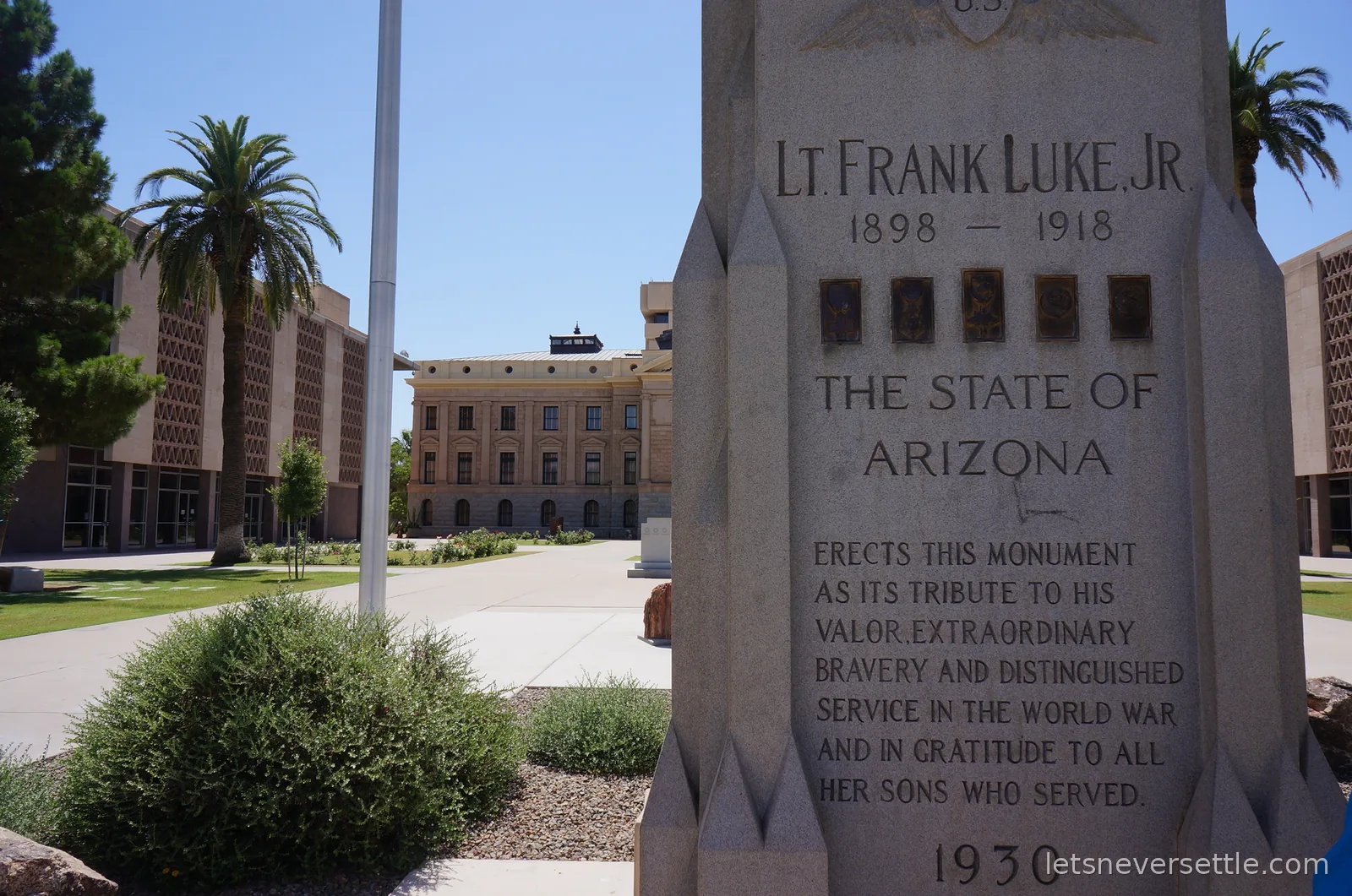 Stone memorial to Lt Frank Luke Jr with palm trees and the Arizona State Capitol behind
