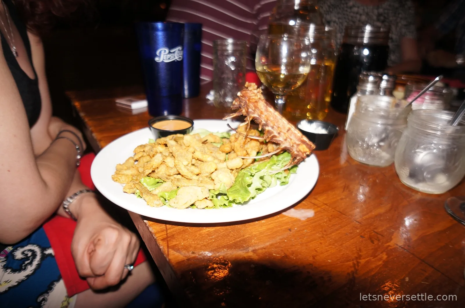 A plate of fried rattlesnake pieces on lettuce with dipping sauce, served with the snake's ribcage across the plate