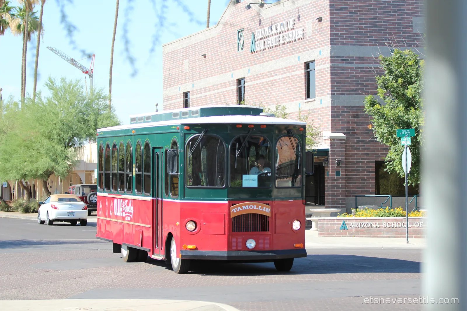 Green and red Ollie the Trolley bus with a Downtown sign in its windscreen turning a corner in Scottsdale