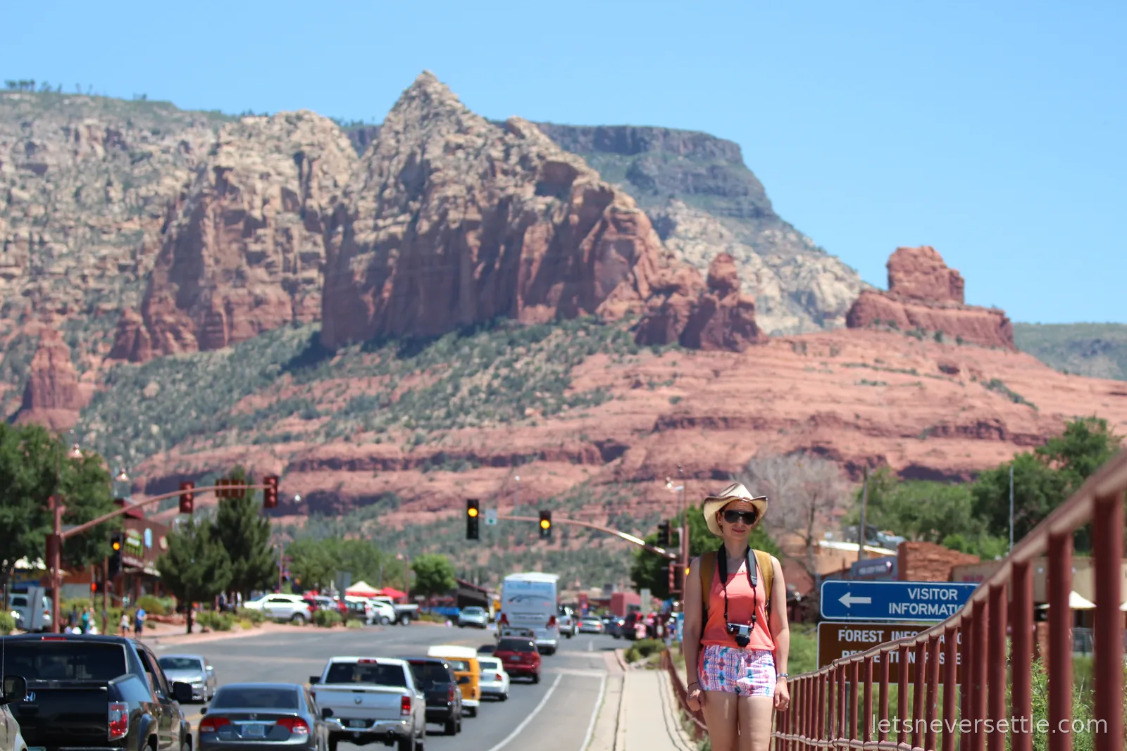 Inga on the sidewalk in Uptown Sedona with shops, traffic and red rocks rising at the end of the street