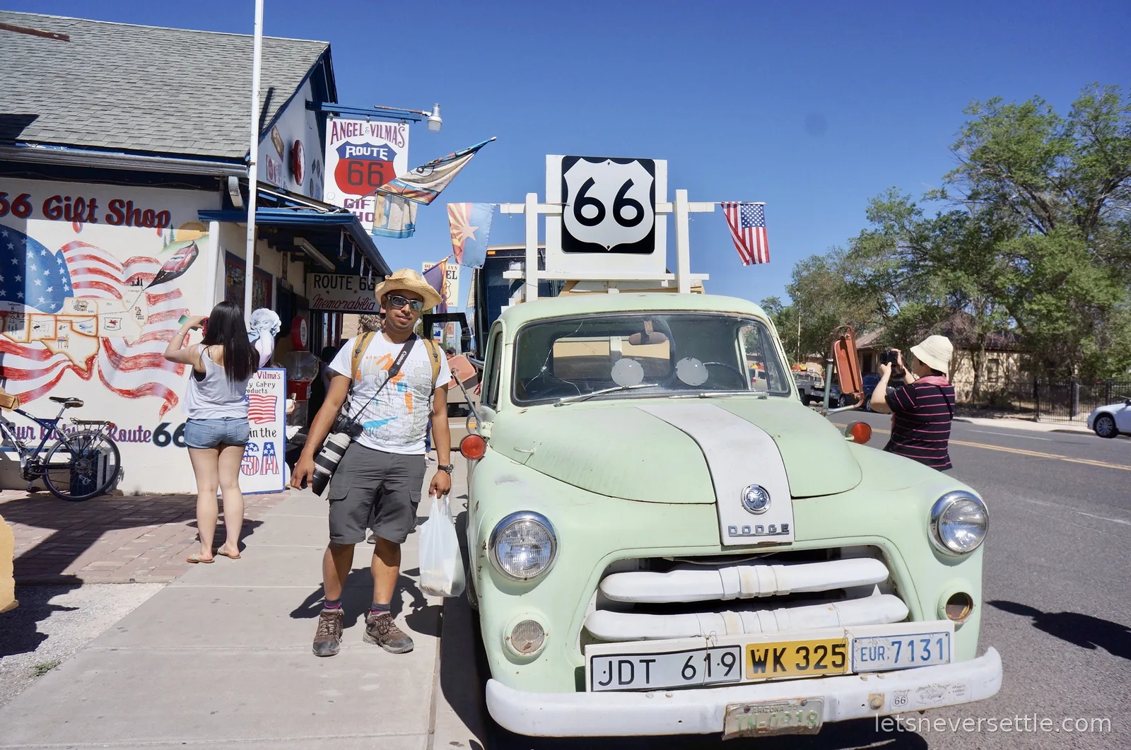 Dileep beside a mint green Dodge pickup truck beneath a US 66 sign outside a gift shop