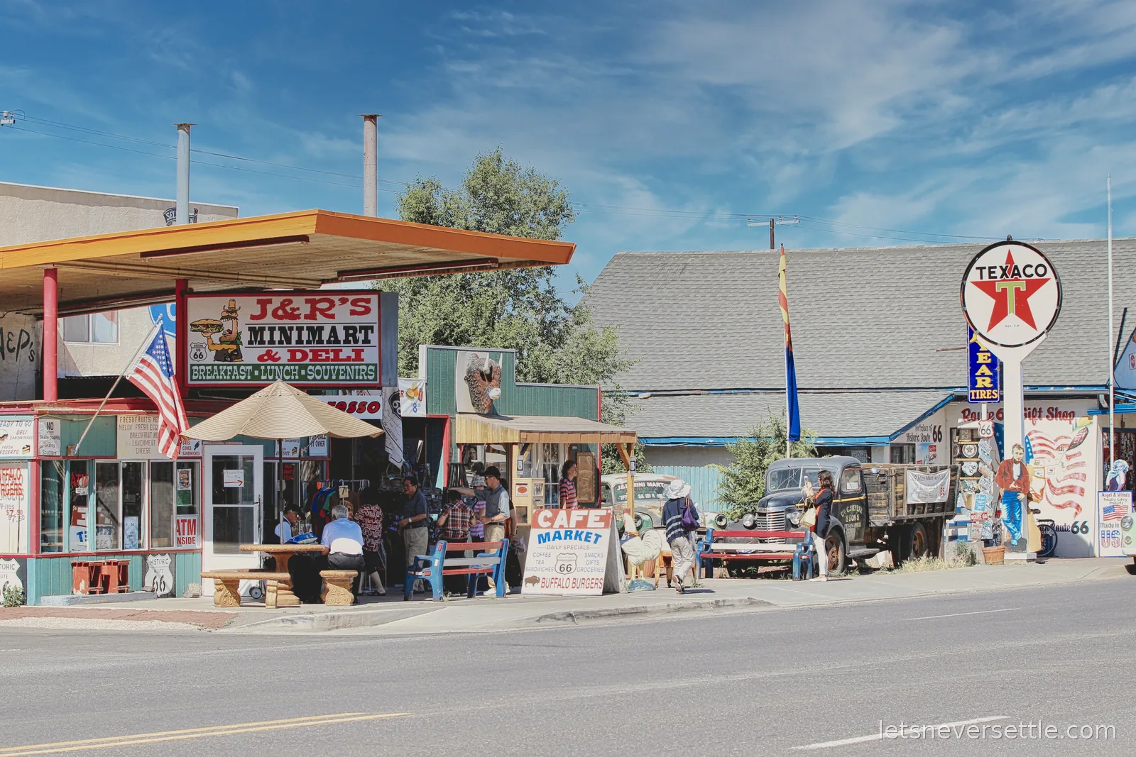 J and R's Minimart and Deli under an orange canopy, with a Texaco sign and Route 66 shopfronts along the street