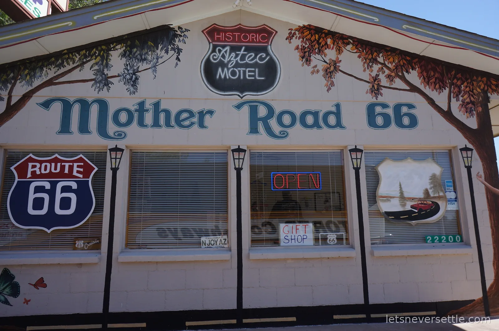 Mural on the Historic Aztec Motel wall in Seligman reading Mother Road 66 with painted Route 66 shields and lamp posts