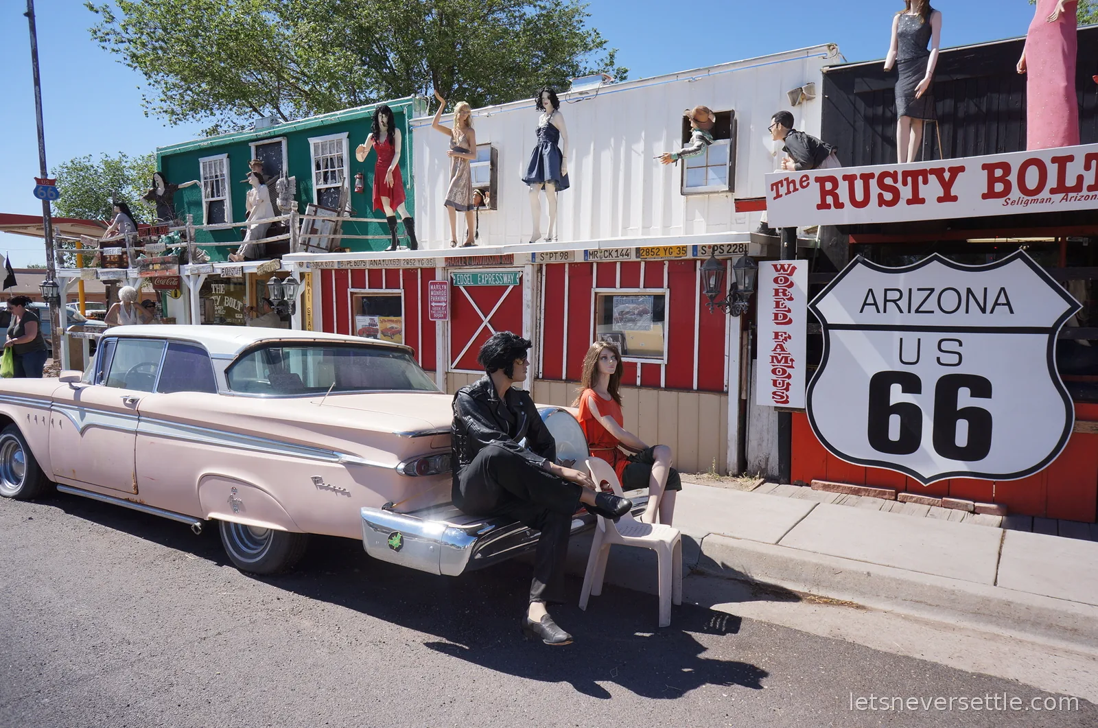 A pink Fifties car with an Elvis mannequin sitting on the boot, parked outside the Rusty Bolt beneath an Arizona US 66 shield