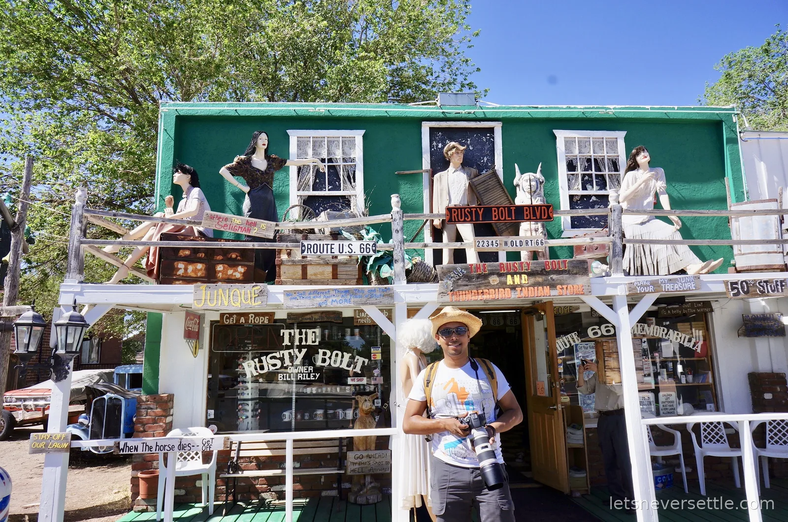 Dileep with his camera outside the Rusty Bolt gift shop, its balcony crowded with dressed mannequins