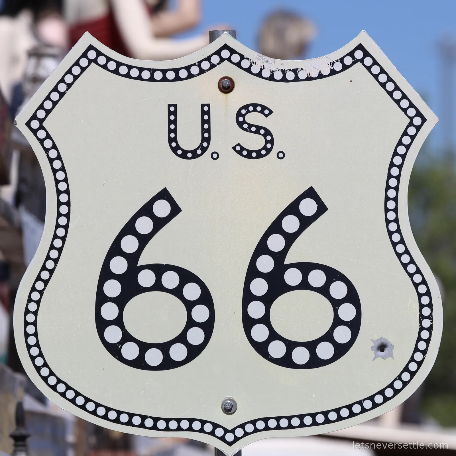 Close-up of a white US 66 route shield sign with a beaded border in Seligman