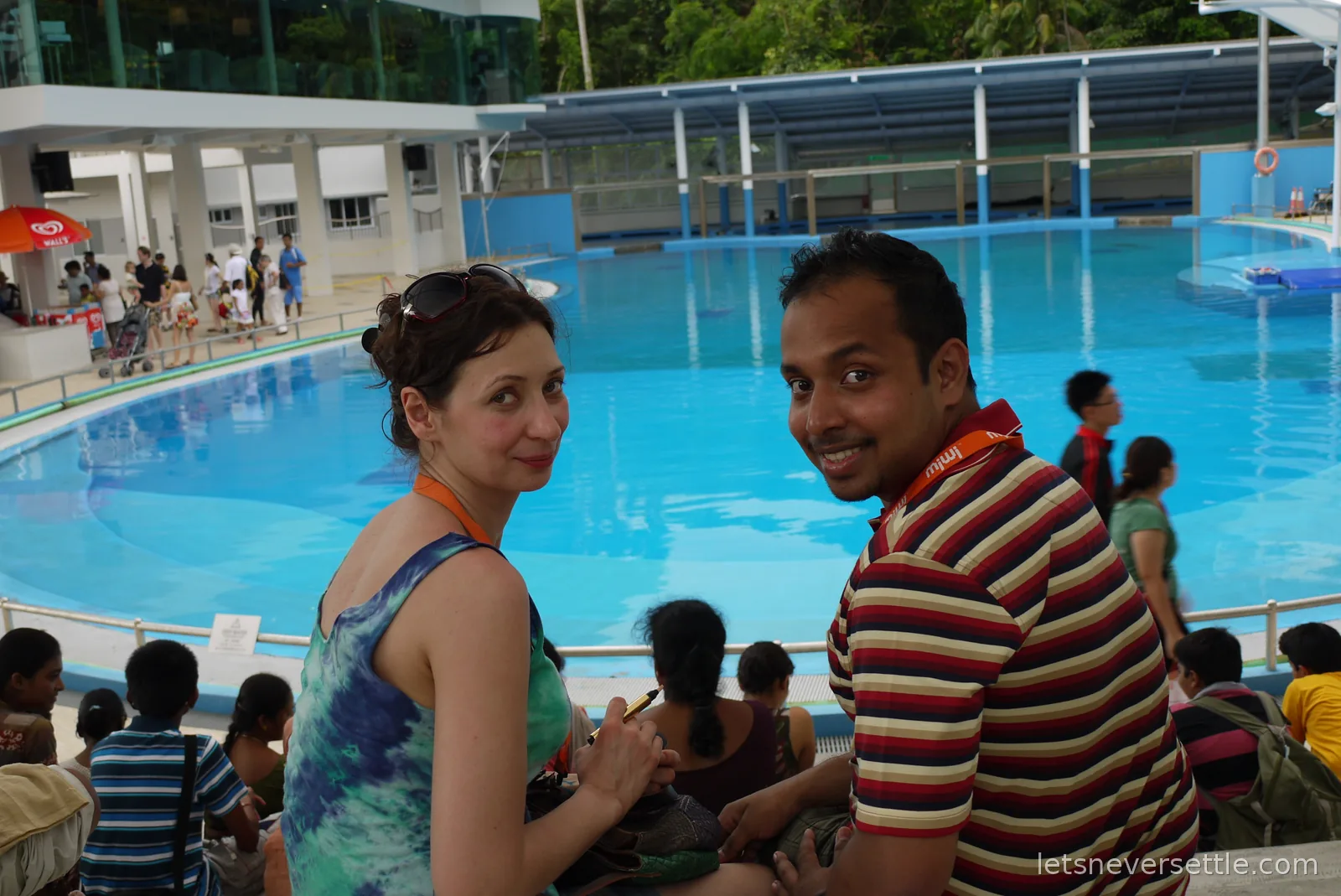 Inga and Dileep looking back from their poolside seats at the dolphin lagoon on Sentosa