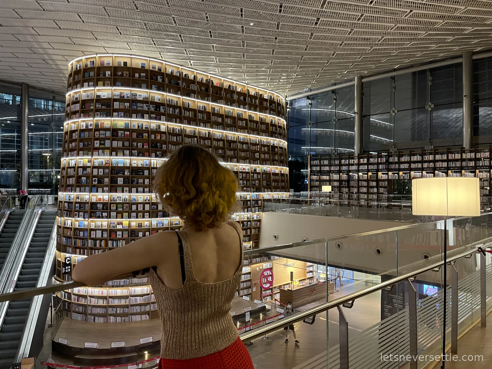 Inga looking out over the towering curved bookshelves of Starfield Library inside COEX Mall
