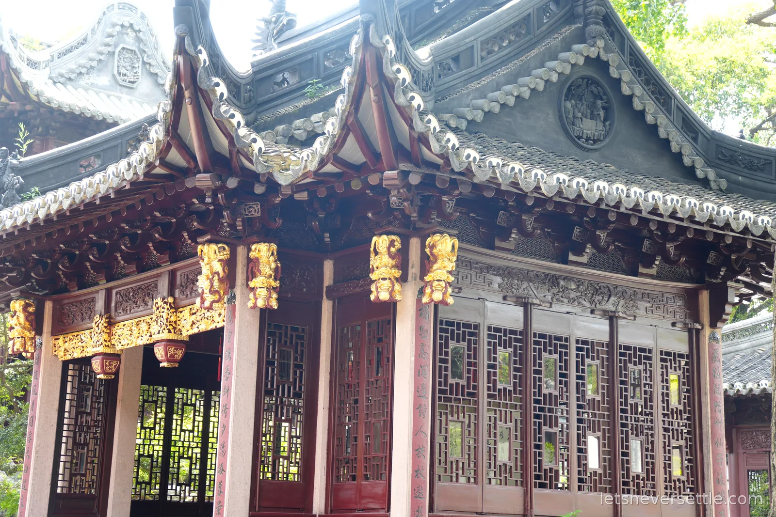A pavilion in Yu Garden with carved grey roof ridges, gilded brackets and dark lattice window screens
