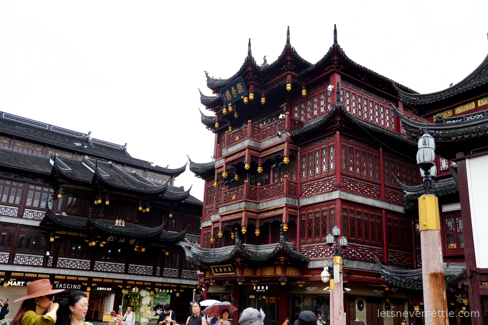 The tiered dark-timber pavilions of the Yuyuan bazaar in Shanghai old town, roof corners curling up under a white sky