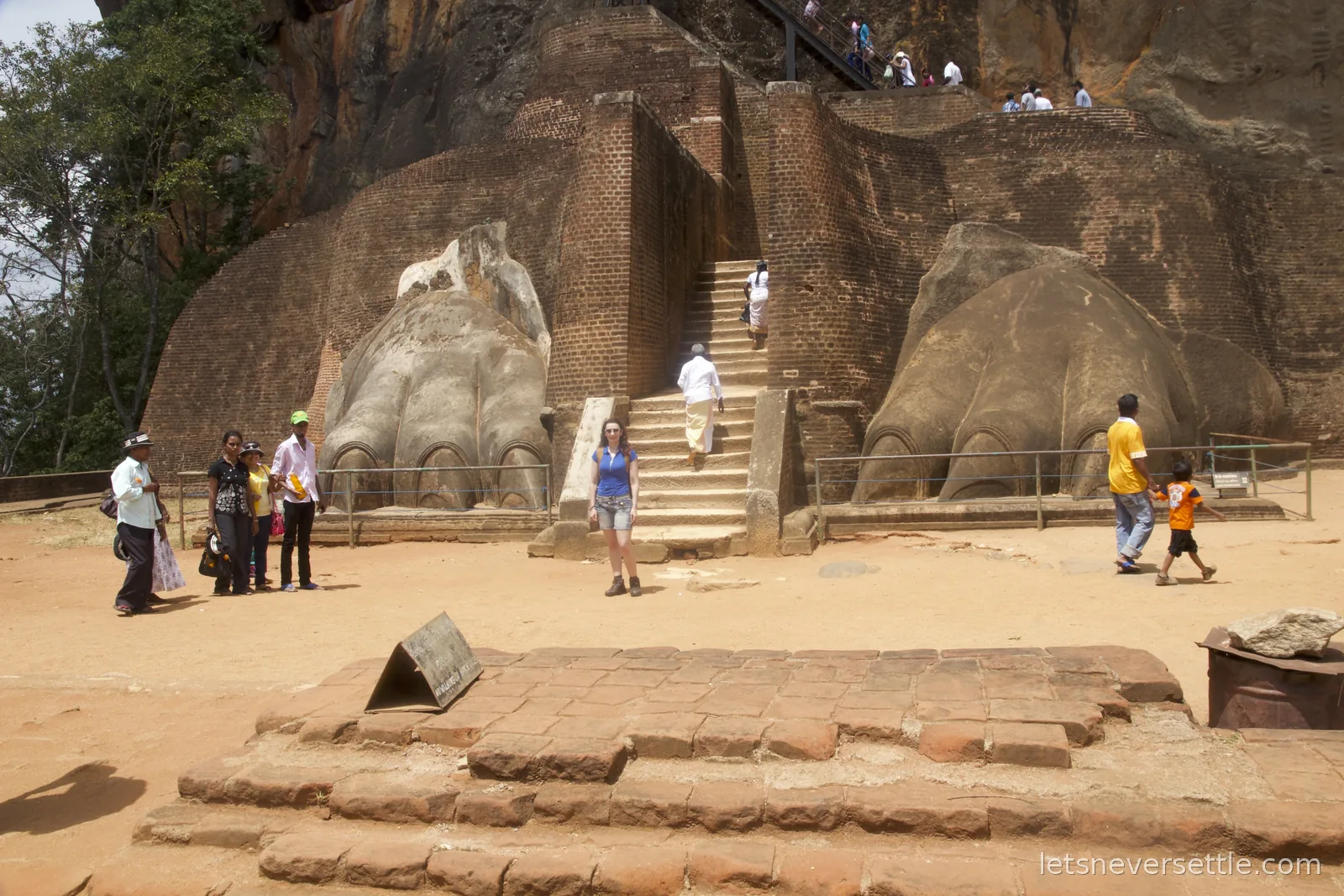 Inga standing between the two giant carved lion paws flanking the brick staircase to the summit of Sigiriya