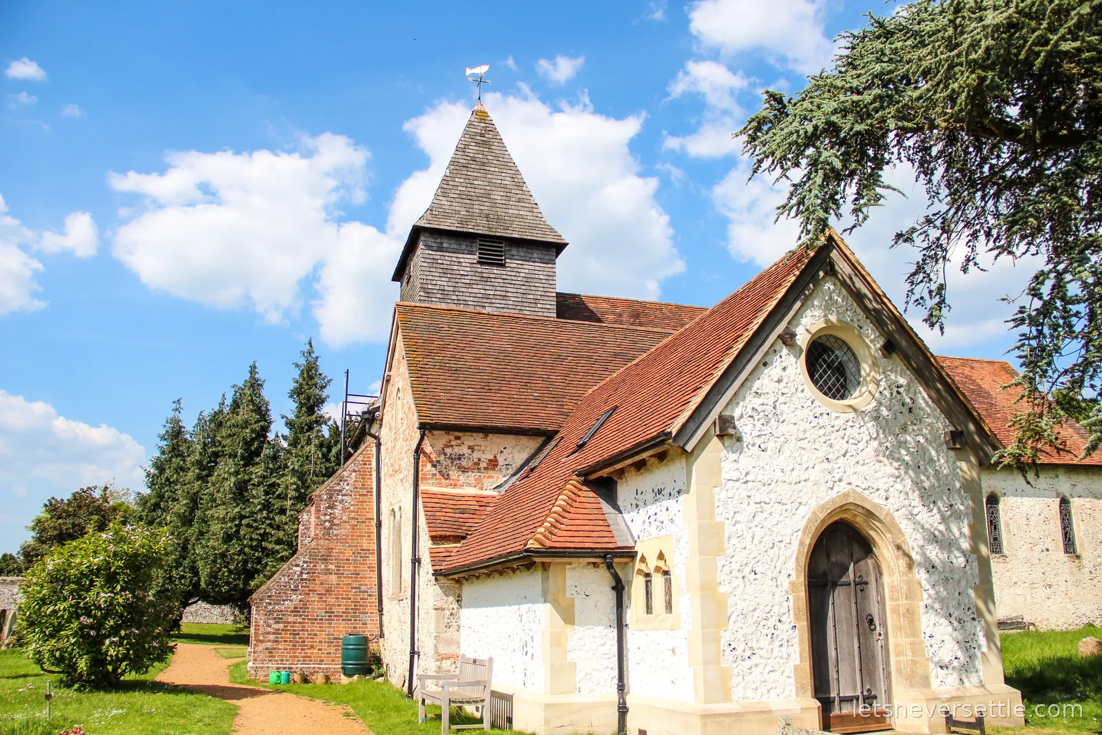 St Mary the Virgin church at Silchester, whitewashed walls, red tiled roofs and a shingled tower under a blue spring sky