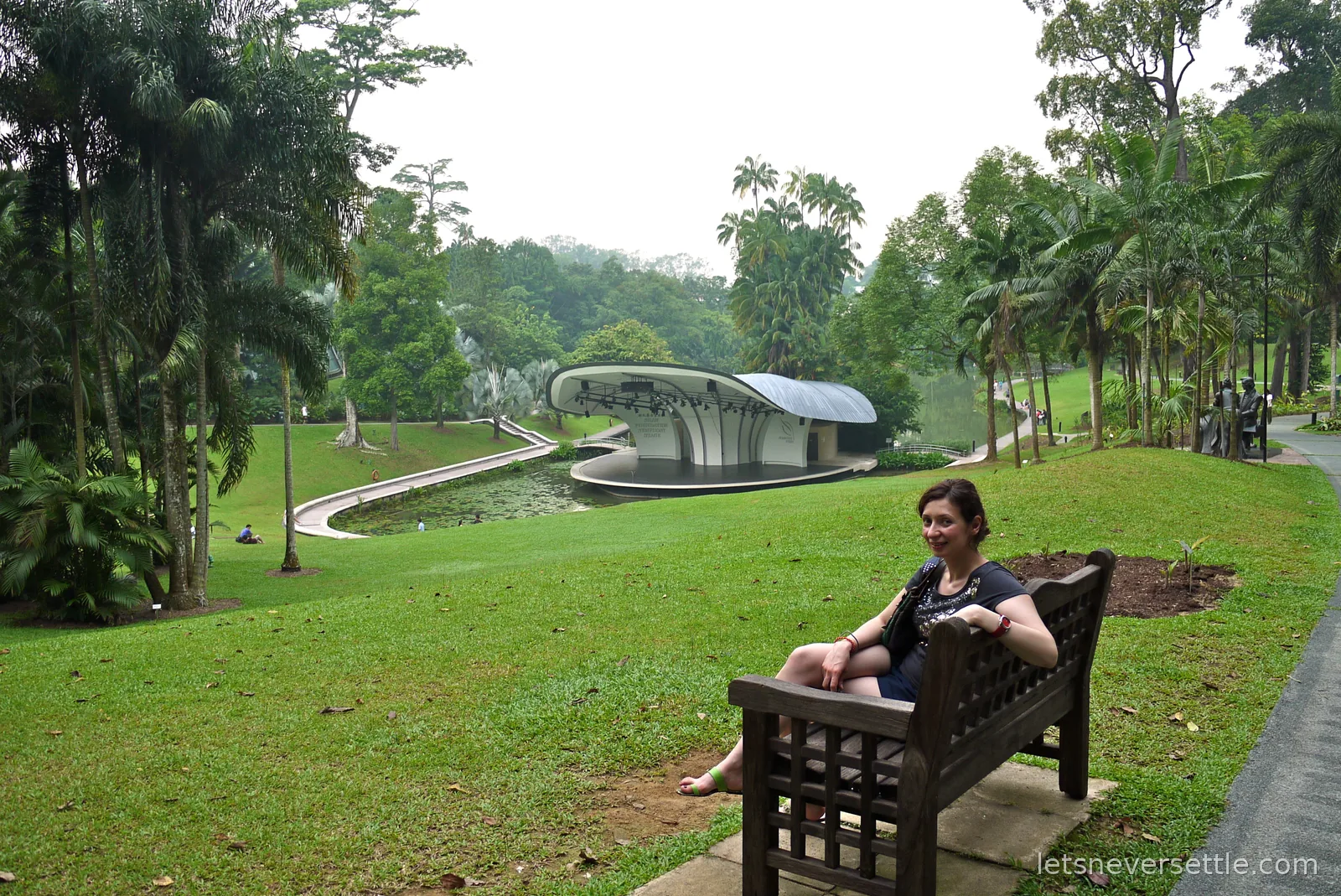 Inga sitting on a wooden bench on the lawn above the Shaw Foundation Symphony Stage in the Singapore Botanic Gardens