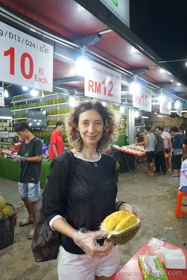 A durian stall in Malaysia with the spiky fruit piled up and labelled by variety