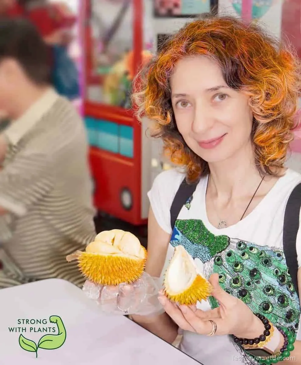 A durian split open showing the pale yellow segments of flesh inside the spiky shell