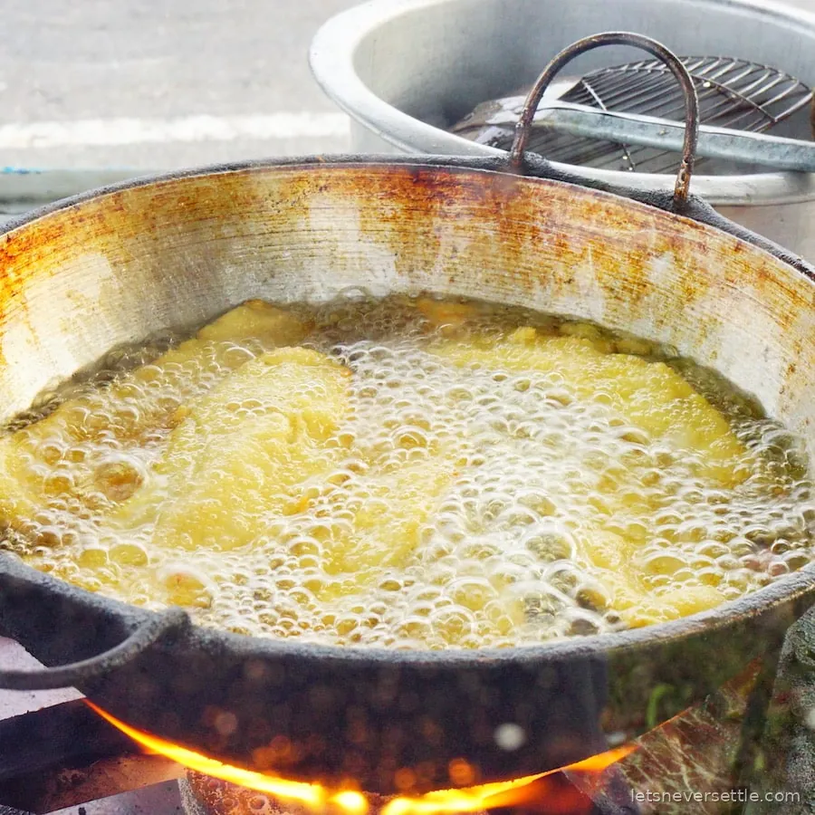 A large pan of oil bubbling over a flame at a Sri Lankan street food stall