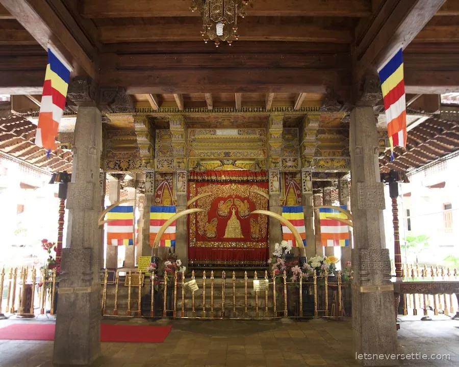 The painted interior of a Buddhist temple in Sri Lanka with Buddhist flags hanging from the columns