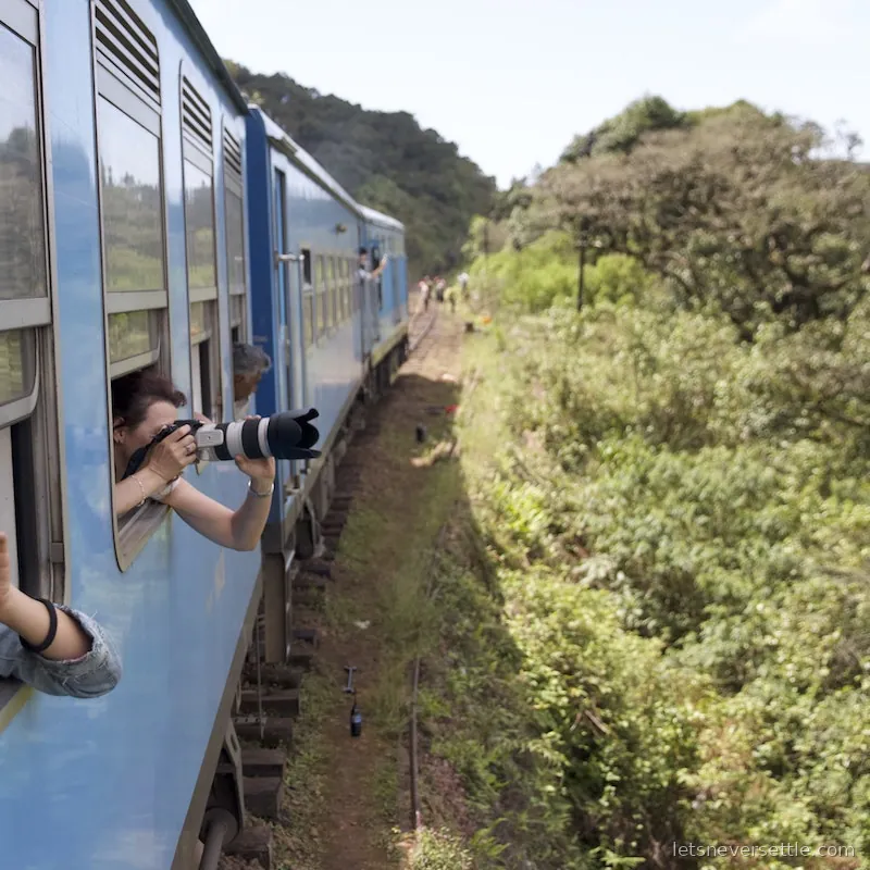 Leaning out of a moving train window in Sri Lanka photographing the green hillside ahead
