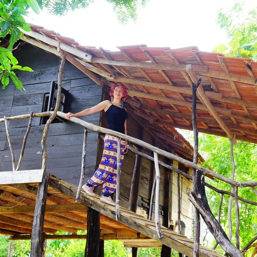 Inga standing on the wooden balcony of a stilted tree house in the Sri Lankan jungle
