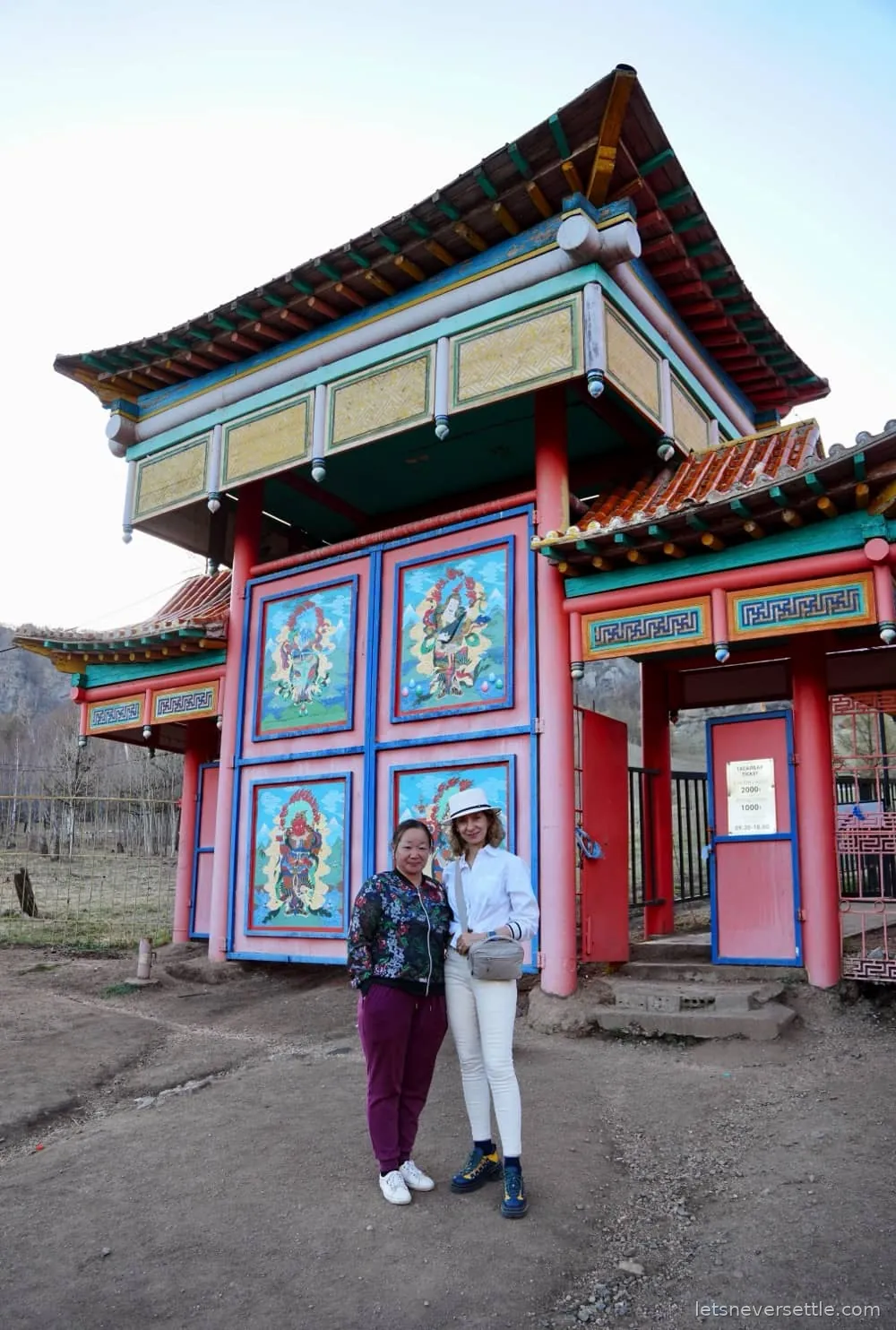 Inga and Dileep standing in front of the brightly painted gate of the Aryabal meditation temple in Mongolia
