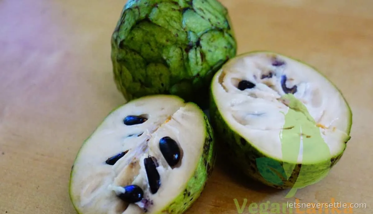 A sugar apple cut in half showing creamy white segmented flesh studded with large smooth black seeds