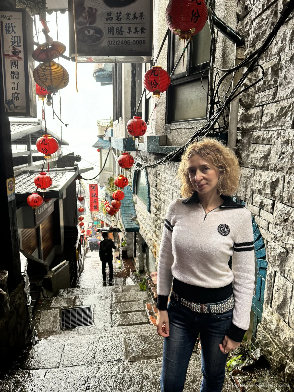 Inga on the narrow stone steps of Jiufen Old Street, strings of red lanterns hanging overhead