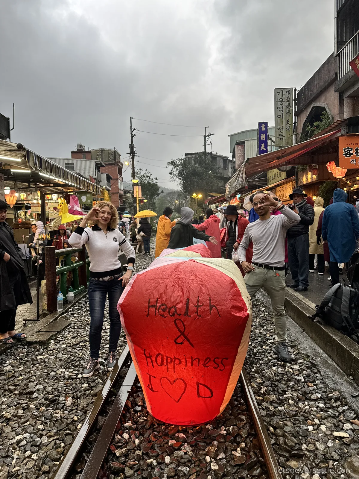Inga and Dileep releasing a red sky lantern with Health and Happiness written on it, on the railway tracks at Shifen