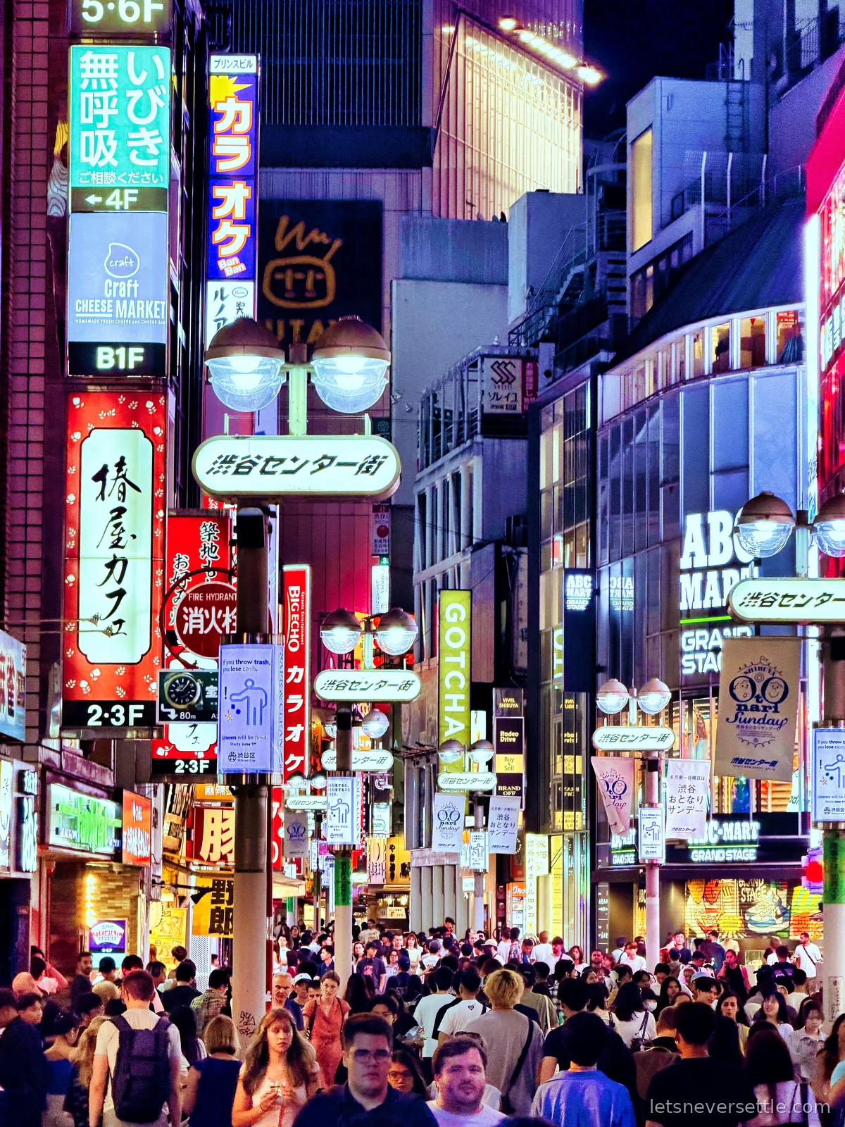 Shibuya Center-gai at night, a narrow street packed with people under layers of neon and backlit signs