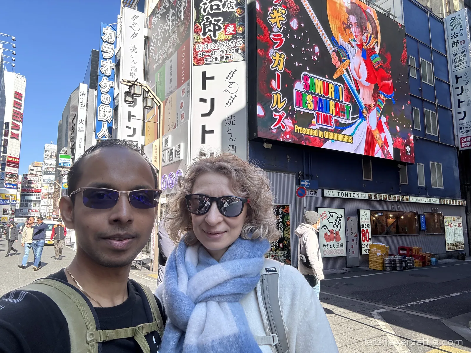Selfie of Dileep and Inga in Kabukicho, Shinjuku, in front of a giant animated billboard for the Samurai Restaurant show