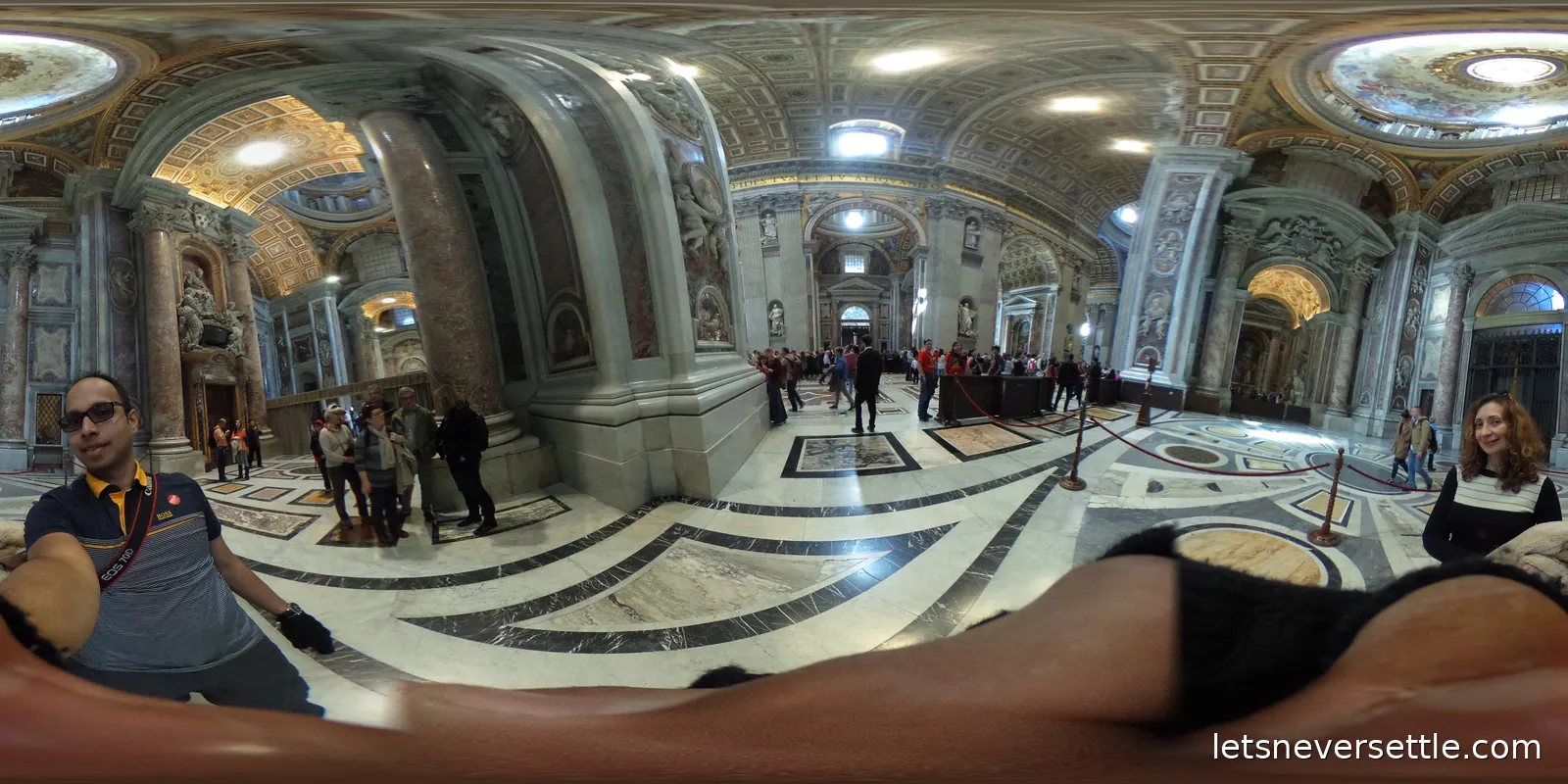 Inside St Peter's Basilica, with enormous marble piers, a patterned marble floor and visitors dwarfed by the scale