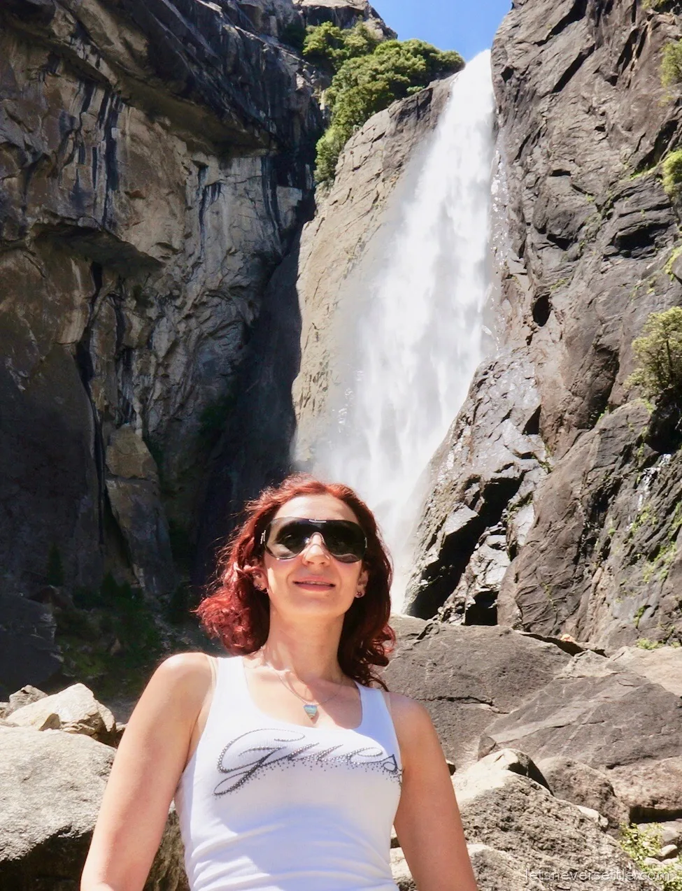 Inga in sunglasses in front of Lower Yosemite Fall pouring down a granite cliff