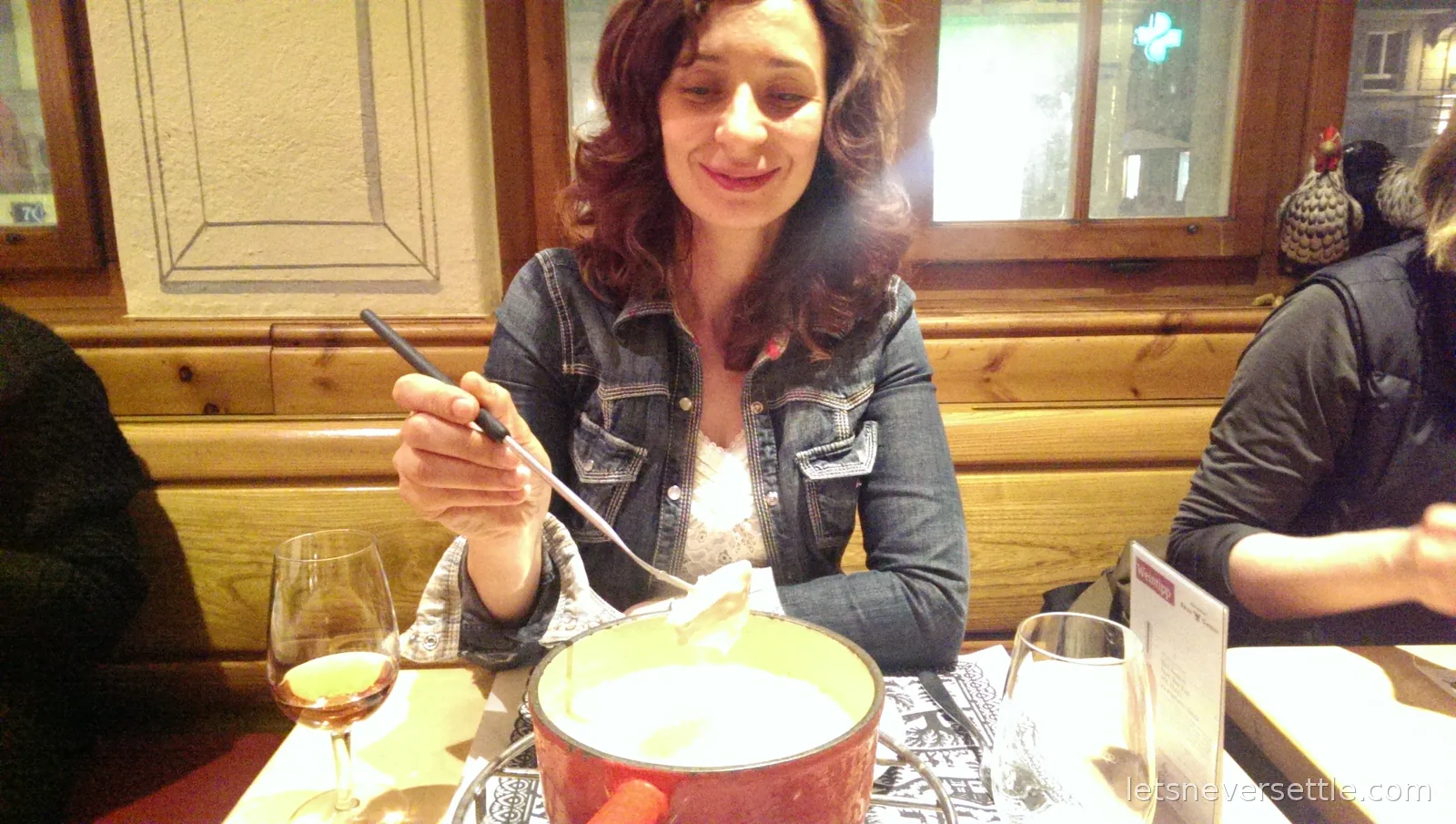 Inga dipping bread on a long fork into a red pot of cheese fondue in a wood-panelled Zurich restaurant