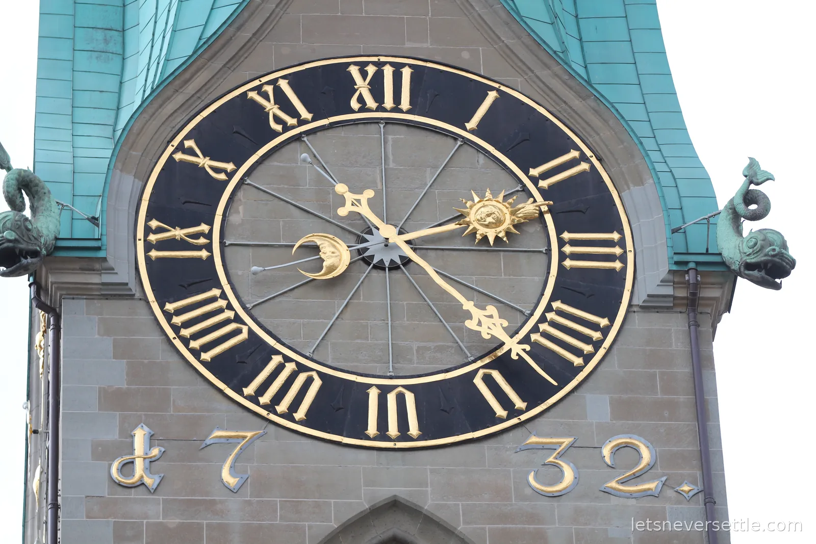 Gilded church clock face in Zurich with sun and moon hands and copper dragon gargoyles either side