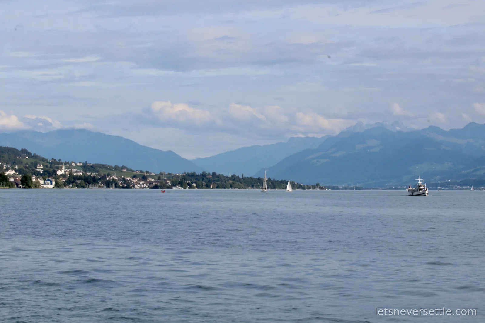 Sailboats and a small ferry on Lake Zurich with the Alps rising in the distance